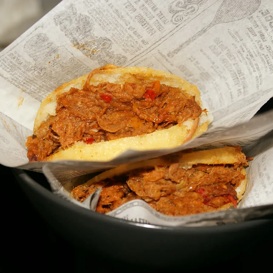 Dos arepas de mechada recién hechas, envueltas en el papel de periódico de la casa