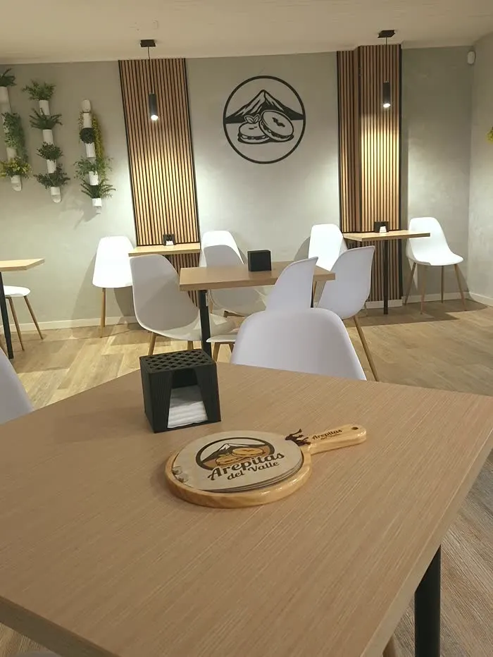 Interior de Arepitas del Valle: el logotipo en la pared de listones y las mesas de madera clara