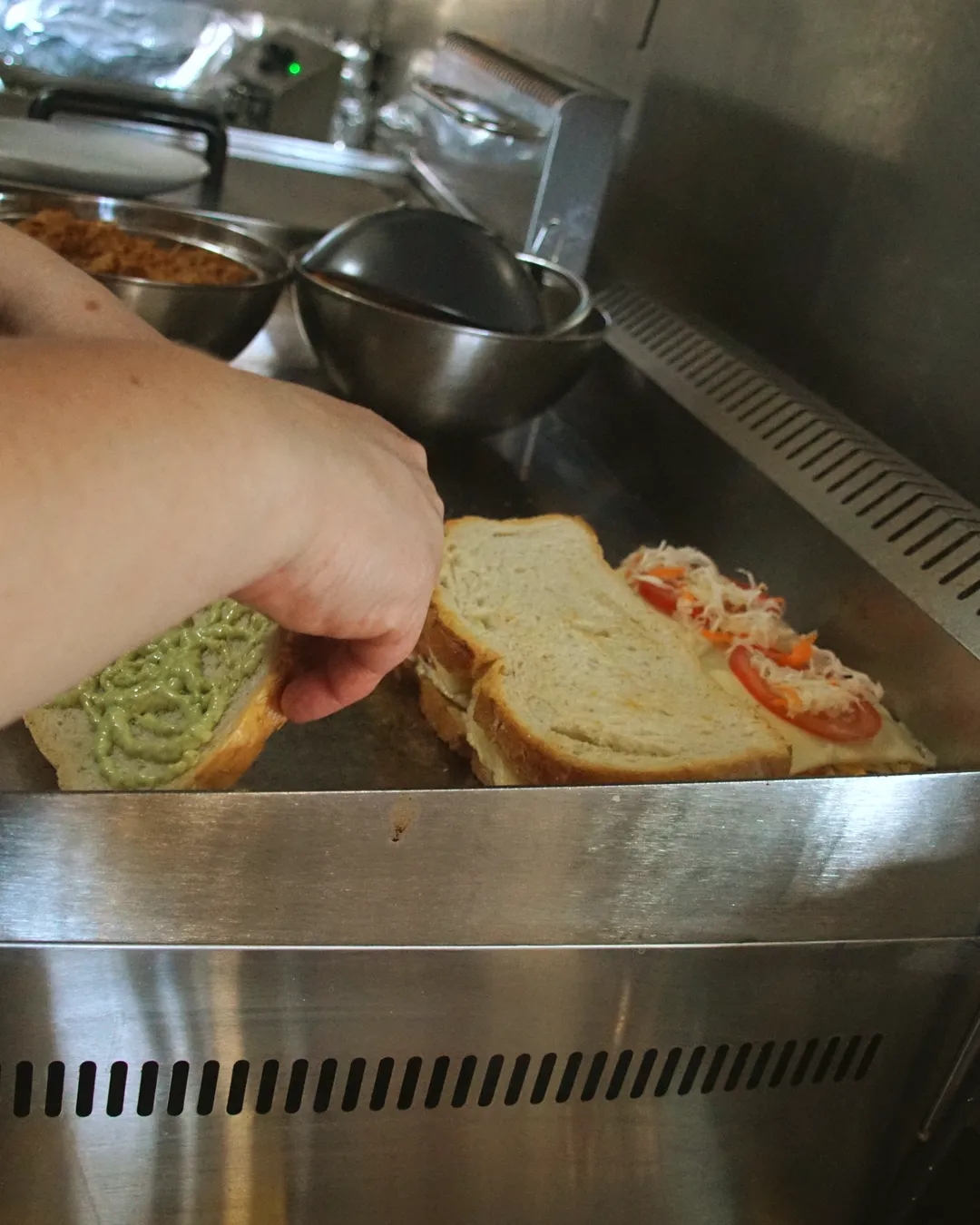 Una mano cerrando el bocadillo sobre la plancha