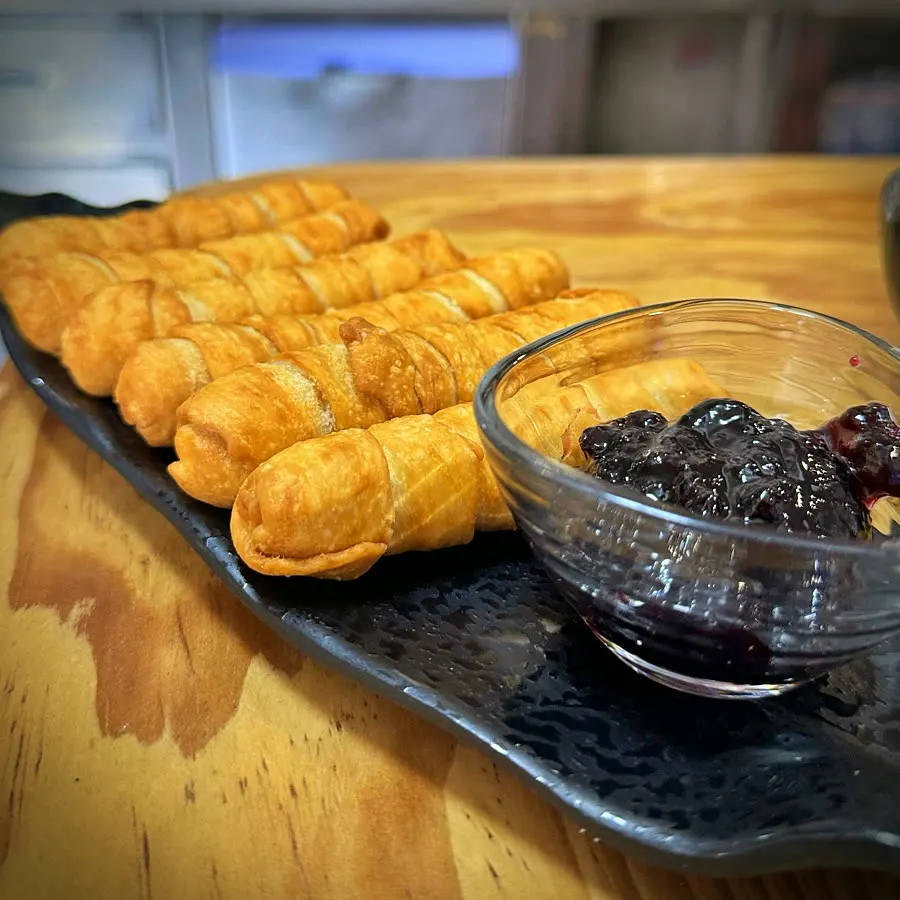 Tequeños recién fritos sobre pizarra, con su salsa